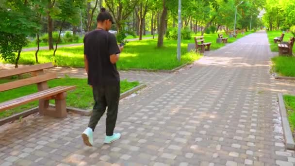 Chico usando mensajes de texto móviles camina en la ciudad — Vídeo de stock