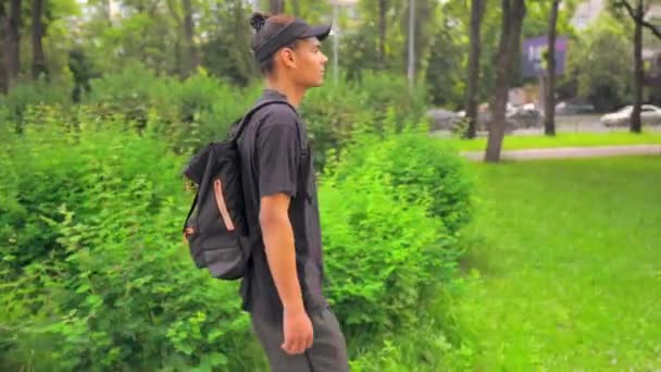 Смешанная раса хипстерский парень, идущий по улице вид сбоку — стоковое видео