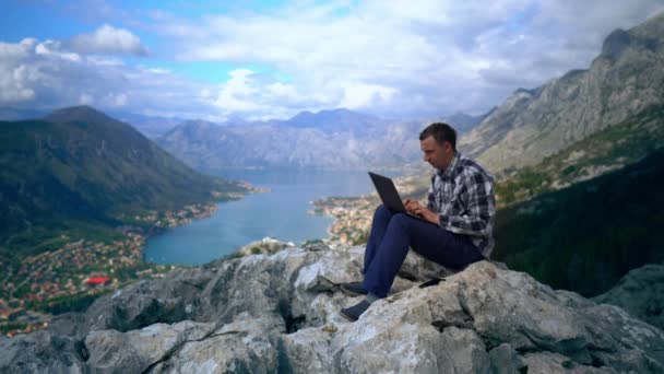Хлопець використовує ноутбук гірський пейзаж влітку — стокове відео