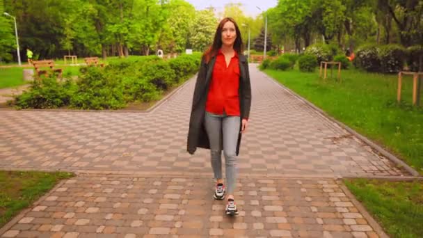 Женщина в сером халате и цветных кроссовках гуляет по городу — стоковое видео