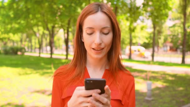 Portrait belle jeune femme rousse bavarder en ligne à l'extérieur — Video