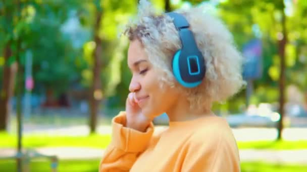 Dziewczyna za pomocą jasnych słuchawek na zewnątrz — Wideo stockowe