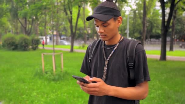 Student mit Rucksack-SMS im Freien — Stockvideo