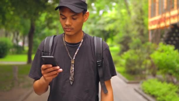 Mensaje de texto de moda de los estudiantes utilizar móvil al aire libre — Vídeo de stock