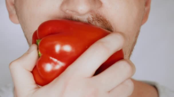 Close up face fair man eats bell pepper — Stock Video