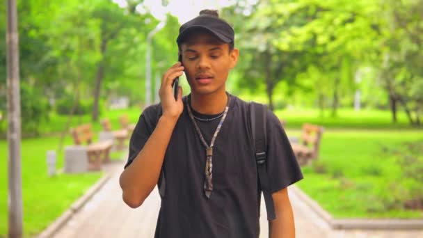 Portre öğrencisi şehirde yürüyor ve cep telefonu kullanıyor. — Stok video