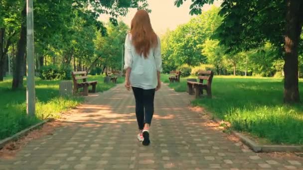 Menina ruiva traseira caminha no parque temporada de verão diurno — Vídeo de Stock
