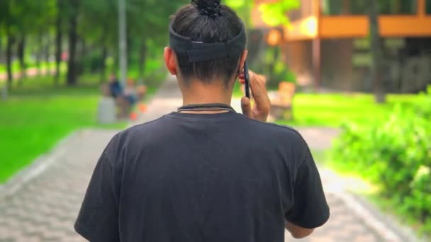 Zpět pohled chlap má telefonní rozhovor na útěku — Stock video