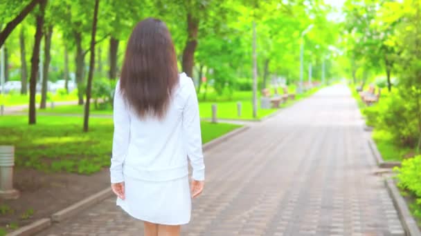 Zpět pohled žena chůze v zeleném parku — Stock video