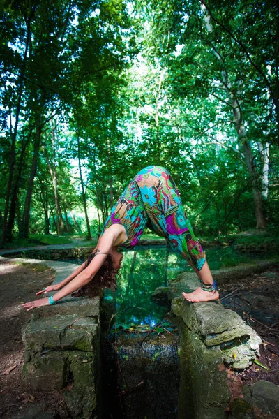 年轻女子练习瑜珈在公园前池塘夏日健康生活方式概念 — 图库照片