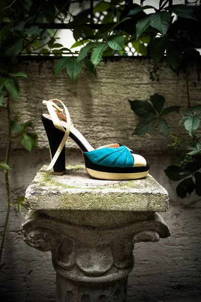 female high heel sandal on column in gaden summer day