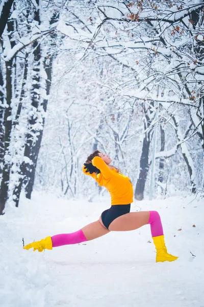 woman fitness instructor workout outdoor in snow park winter day