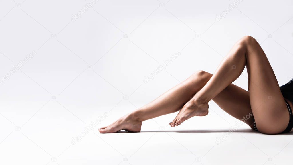 long tanned slim woman legs studio shot sit down white background 