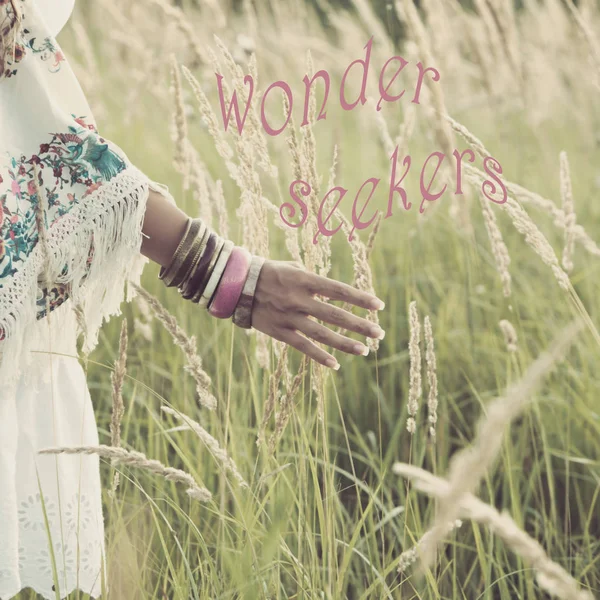 Woman hand with lot of boho style braceletes touching grass , su — Stock Photo, Image