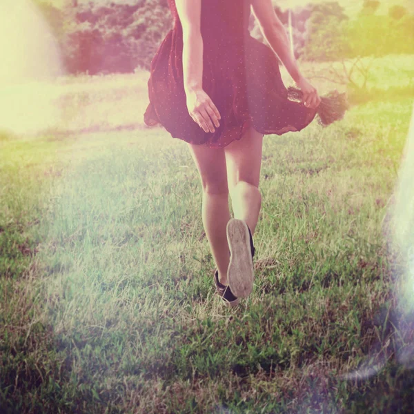 Молода жінка біжить через поле назад знімок нижнього тіла літнього дня — стокове фото