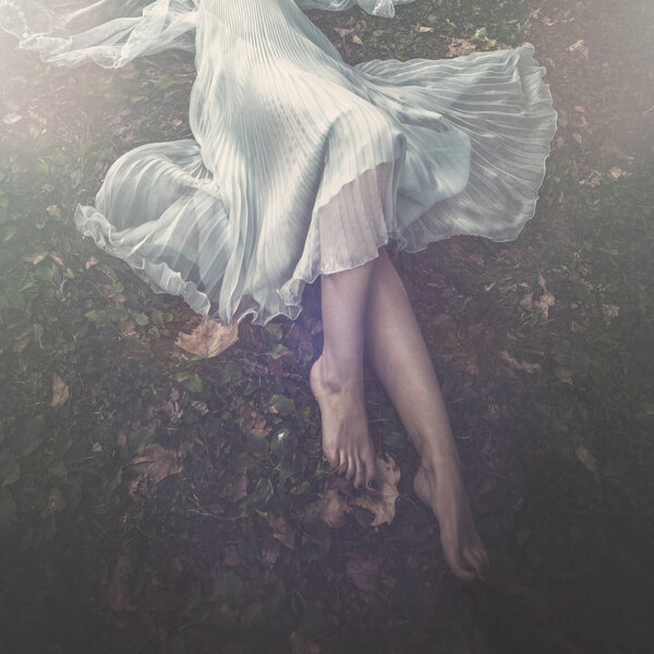 Barefoot woman lie on grass in elegant dress lower body summer day