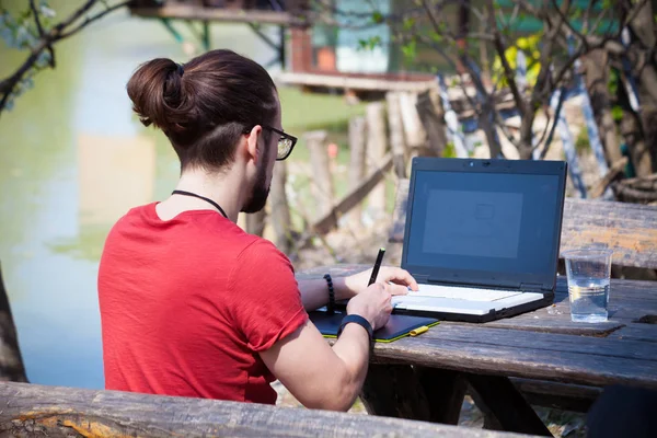 Młody nowoczesny człowiek freelancer projektant pracuje na świeżym powietrzu nad jeziorem na — Zdjęcie stockowe