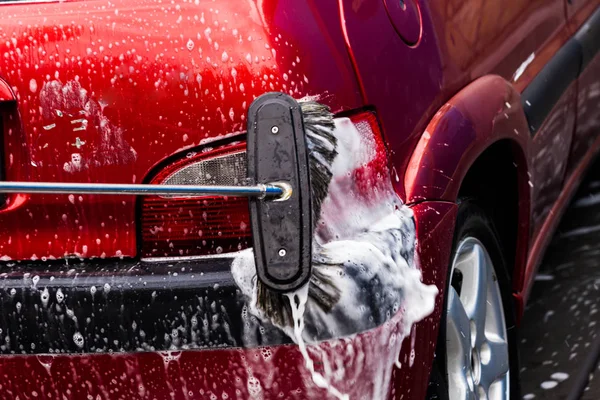 Ręczne mycie samochodu wodą pod ciśnieniem i mydłem w myjni samochodowej o — Zdjęcie stockowe
