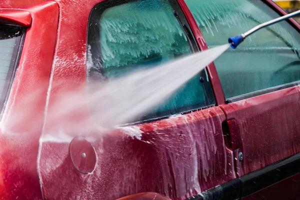 Ręczne mycie samochodu wodą pod ciśnieniem i mydłem w myjni samochodowej o — Zdjęcie stockowe