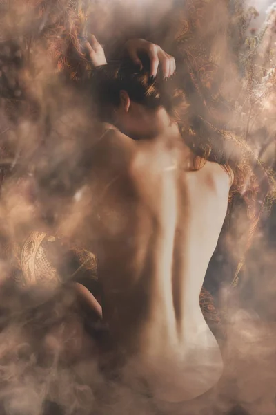 年轻女子赤裸裸地回到浅棕色梦幻般的烟雾 — 图库照片