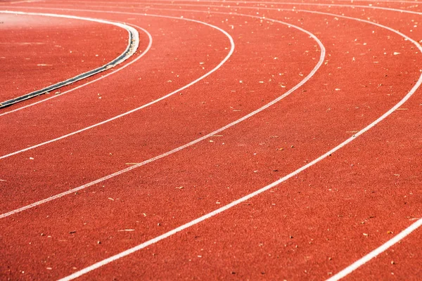 Athletic red running tracks whit white lines and some leaves on — Stock Photo, Image