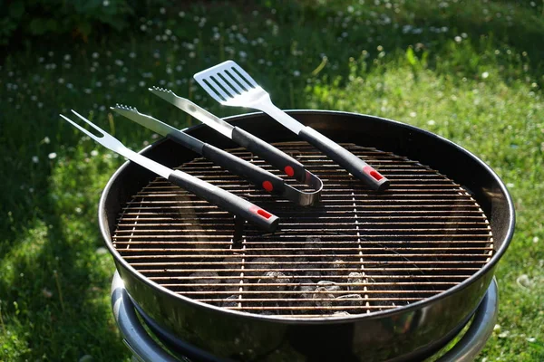 Cutlery for sausages barbecue with a charcoal barbecue in the garden