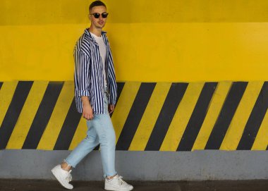 çizgili giyim sarı bir duvarının yakınında duran moda adam