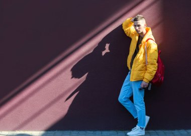 sarı giysili bir Viyola duvarının yakınında duran moda adam