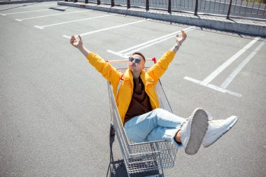 moda erkek güneş gözlüğü ve sarı ceket bir sepeti süpermarket Park gıdalardan oturuyor