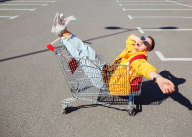 moda erkek güneş gözlüğü ve sarı ceket bir sepeti süpermarket Park gıdalardan oturuyor