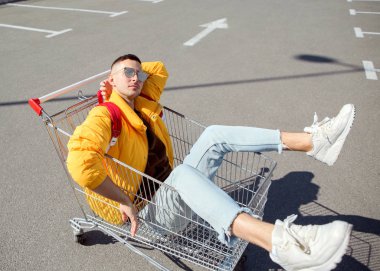 moda erkek güneş gözlüğü ve sarı ceket bir sepeti süpermarket Park gıdalardan oturuyor