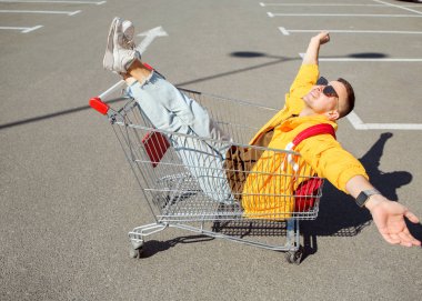 moda erkek güneş gözlüğü ve sarı ceket bir sepeti süpermarket Park gıdalardan oturuyor