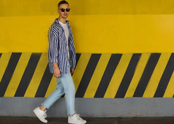 ストライプの服に黄色の壁の近くに立ってファッションの男 — ストック写真