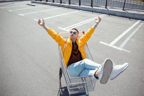 moda erkek güneş gözlüğü ve sarı ceket bir sepeti süpermarket Park gıdalardan oturuyor