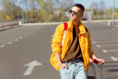 moda erkek güneş gözlüğü ve sarı ceket bir sepeti süpermarket Park Gıda üzerinden atlamak