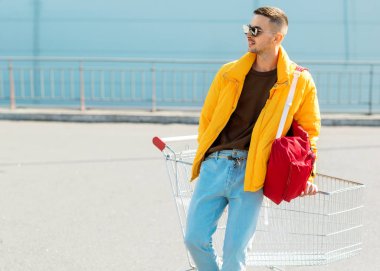 moda erkek güneş gözlüğü ve sarı ceket bir sepeti süpermarket Park Gıda üzerinden atlamak