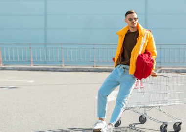 moda erkek güneş gözlüğü ve sarı ceket bir sepeti süpermarket Park Gıda üzerinden atlamak