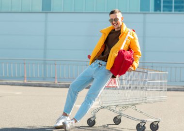 moda erkek güneş gözlüğü ve sarı ceket bir sepeti süpermarket Park Gıda üzerinden atlamak