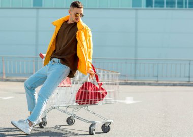 moda erkek güneş gözlüğü ve sarı ceket bir sepeti süpermarket Park Gıda üzerinden atlamak