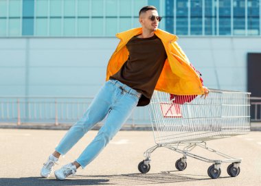 moda erkek güneş gözlüğü ve sarı ceket bir sepeti süpermarket Park Gıda üzerinden atlamak