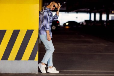 çizgili bir gömlek moda adam sarı Park duvara yakın duruyor