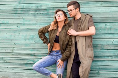 moda çift ayakta yeşil ahşap duvara yakın poz