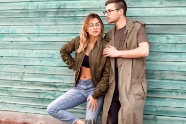 moda çift ayakta yeşil ahşap duvara yakın poz