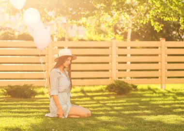 güzel kız güzel bir elbise ve şapka çimenlerin üzerinde oturur