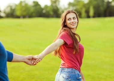 bir kızın elini tutarak aşık adam ve onlar parkta yürümek