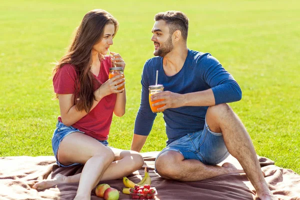 愛のカップルがピクニックで公園や飲み物スムージー 食べる果物で楽しい時を過す — ストック写真