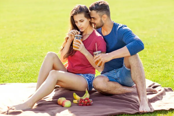 愛のカップルがピクニックで公園や飲み物スムージー 食べる果物で楽しい時を過す — ストック写真