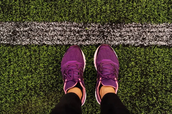 从上面的腿的看法在紫色的运动鞋在橄榄球场 — 图库照片