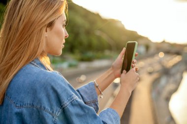kız bir manzara, gün batımında onun elinde bir telefon yakın çekim fotoğraf çekmek