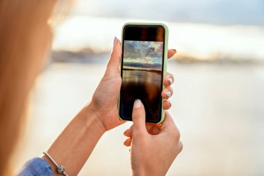 kız bir manzara, gün batımında onun elinde bir telefon yakın çekim fotoğraf çekmek